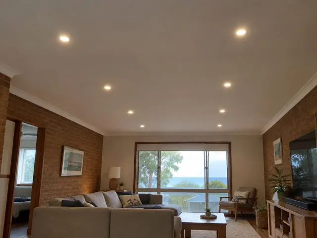 Living room ceiling with recessed LED downlights above brick walls and ocean view in Forresters Beach