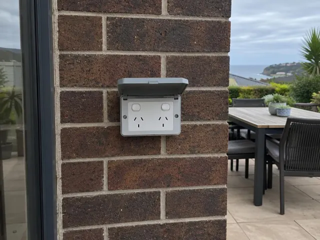 Outdoor double power point on a brick patio wall beside a deck and water view in Shelly Beach